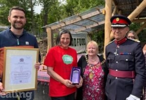 4 people standing looking happy - one holding a certificate and another holding an award