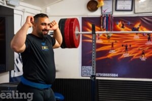 weightlifter in gym standing by weights flexing his muscles