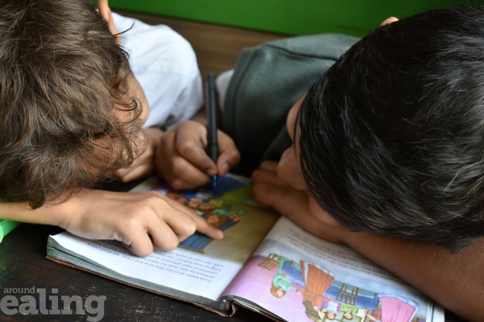 Two young boys closely reading a school reading book together