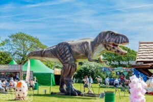 huge T-Rex model in outdoor setting with people enjoying the experience