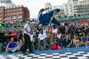 Photo of young person doing a backflip on a dancefloor with crowd watching behind