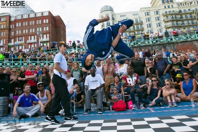 Photo of young person doing a backflip on a dancefloor with crowd watching behind