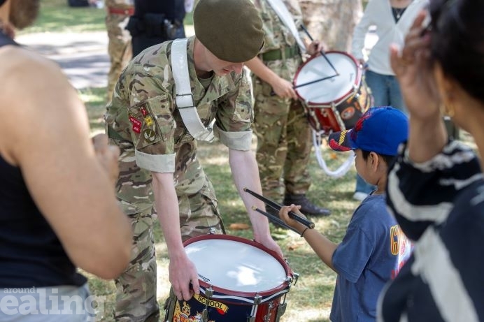 Cadet showing little boy to drum