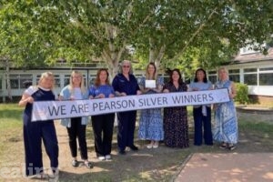 Teachers from Stanhope Primary School holding up a banner which says "We are Pearson silver winners"