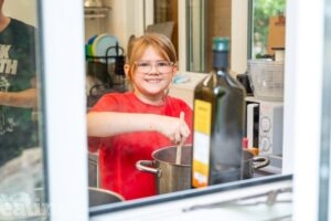 girl in kitchen stirring food in a saucepan