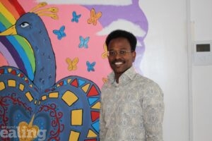 Dr Ahmed Herzi, peer researcher at Voices for SEND, in front of a colourful mural