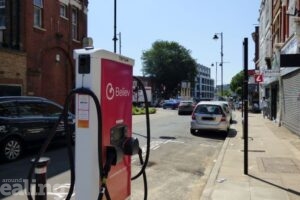 Believ-branded Electric vehicle charging point on a high street in the borough of Ealing, with cars and shops in the background