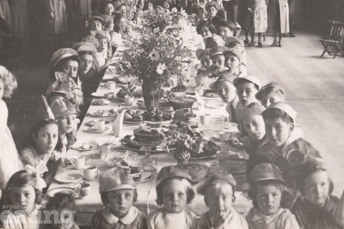 sepia image of children and women enjoying a big tea party to celebrate VJ Day in Southall