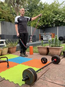 Mohamed doing exercises with elastic bands in a garden