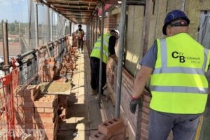 2 construction workers on site working outdoors with scaffolding