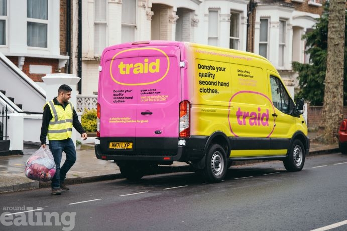 Man wearing hi-vis jacket carrying a clear sack of textiles next to a 'traid' branded van