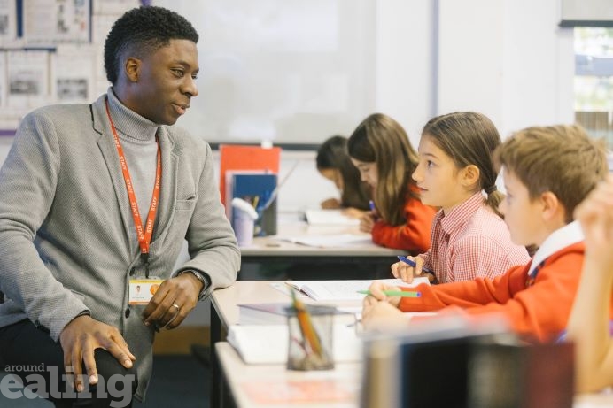 headteacher kneeling to chat to 2 pupils in classroom