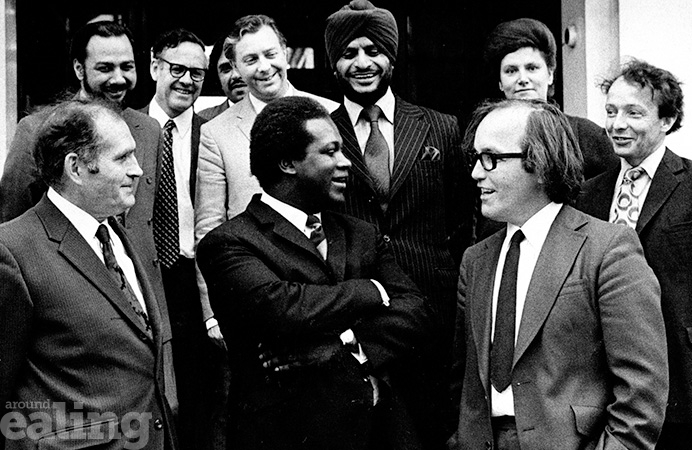 Group of men wearing suits and ties, chatting and smiling in the 1970s