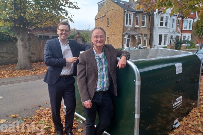 Council Leader Peter Mason and cabinet member for climate action, Paul Driscoll, stood leaning against a green bike hangar
