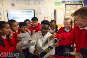 Footballer Bukayo Saka visiting Edward Betham Primary - his old school - surrounded by pupils asking for autographs