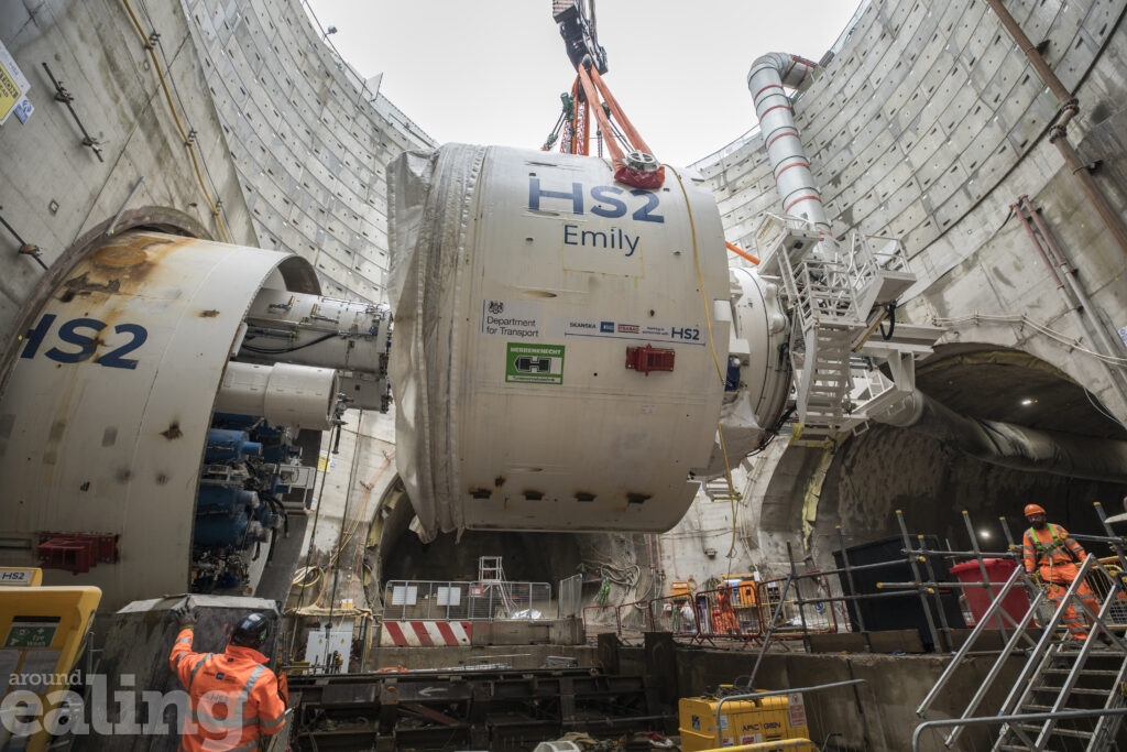 Crane lifting large piece of machinery out of a bore-hole, with HS2 Emily written on the side