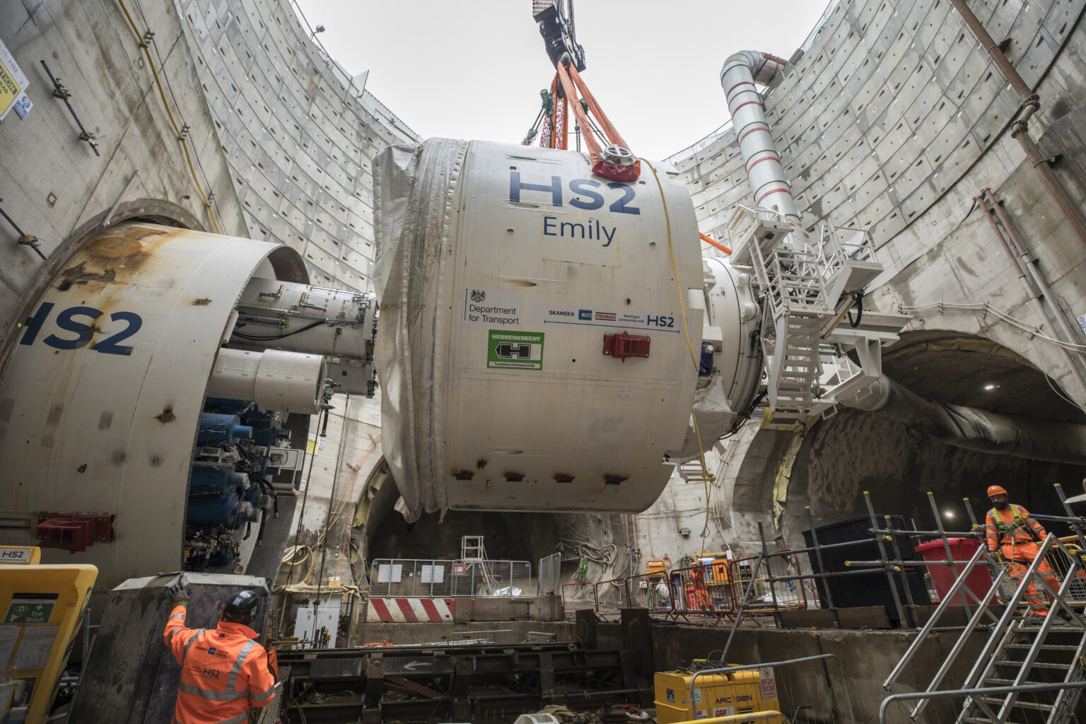 Crane lifting large piece of machinery out of a bore-hole, with HS2 Emily written on the side