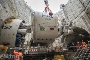 Crane lifting large piece of machinery out of a bore-hole, with HS2 Emily written on the side