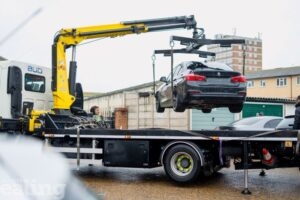 Black car suspended in the air by a tow truck