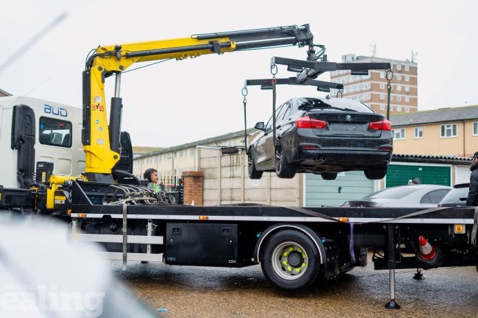 Black car suspended in the air by a tow truck