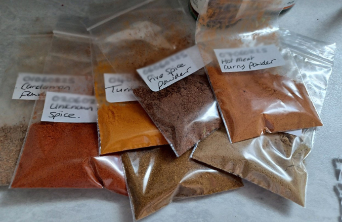 Small bags of spices on a table, each packet is labelled