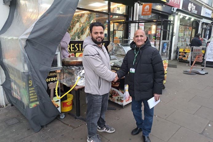 Shop owner shaking hands with Ealing Council's waste commercial sales officer in front of high street shops
