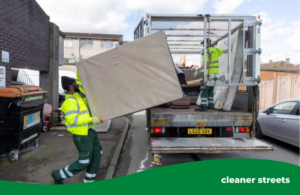 Greener Ealing operative lifting a mattress onto a fly-tip caged vehicle