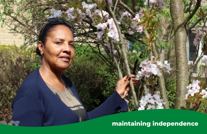 A woman, who is carer Josephine, standing in a garden next to a tree