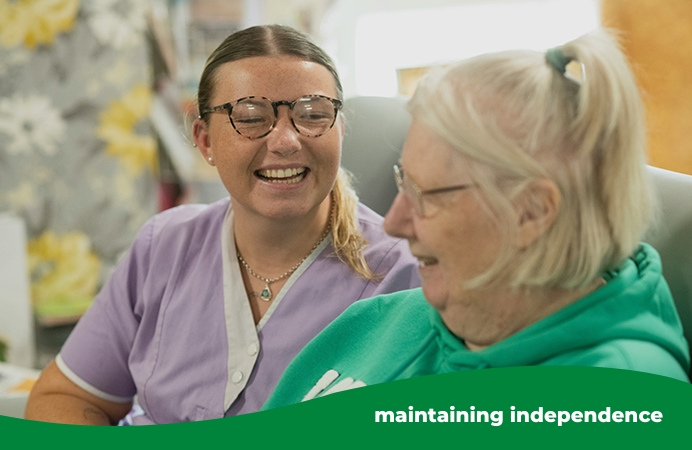 Two women, one younger and one older, laughing together on a sofa