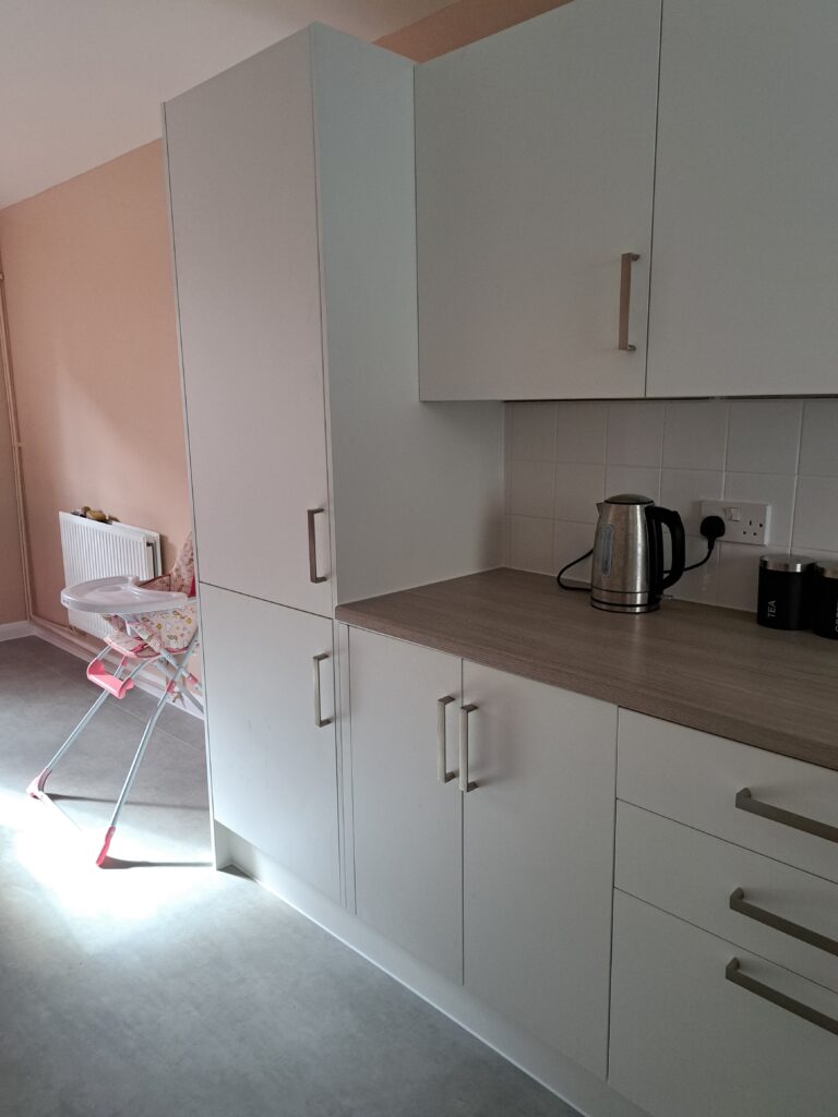 Kitchen area with a kettle on the counter, high chair and radiator