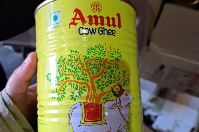 Someone holding a yellow packet of ghee. Package says Amul cow ghee