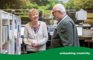 man and woman library volunteers smiling in conversations at the bookshelves