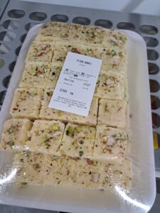 Pack of Indian dessert, called barfi, with pistachio on the top