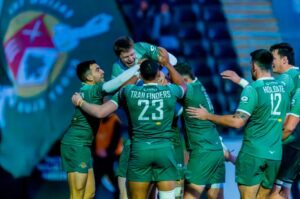 male rugby players in a green kit celebrating