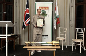 Chloe Kelly standing on a stage, holding a certificate, with flags either side of her and the mayor's ceremonial mace laying on a table in front of her