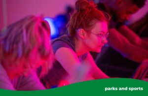 A woman deep in concentration sitting on an exercise bike during a group cycling fitness class.