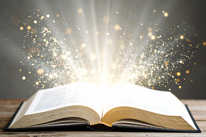An open book with streams of light and sparkles coming out