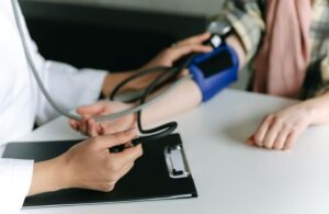 Close up of an arm with a strap around it, and two hands with a clip board