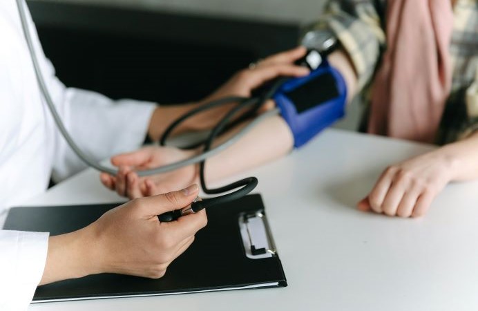 Close up of an arm with a strap around it, and two hands with a clip board