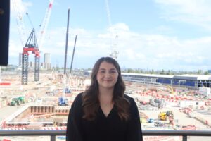 A woman smiling at the camera, with construction works in the background