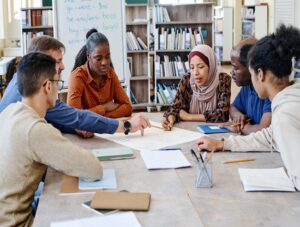 A group of learners from different ethnic backgrounds sat at a table in a library