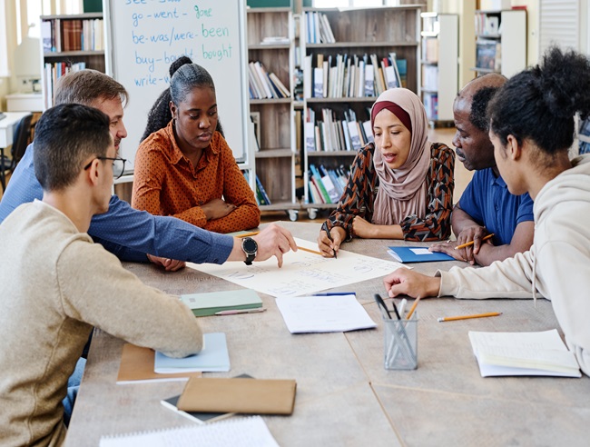 A group of learners from different ethnic backgrounds sat at a table in a library