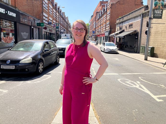 Samantha Steggles is wearing a pink sleeveless jumpsuit standing in the middle of Bond Street in Ealing with cars on either side of her.