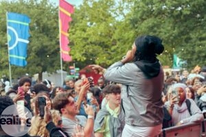performer on stage with mic and crowds of young people watching