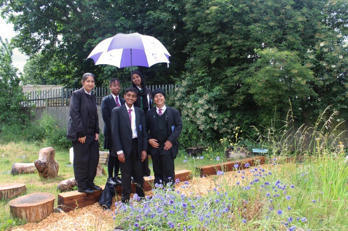 Five school children standing in a garden in the school's grounds