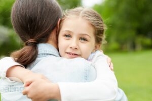 An image of a young girl with her arms around her foster mother