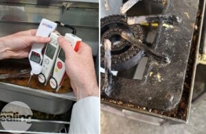 A hand holding three thermometers in a dish of food and a dirty gas hob