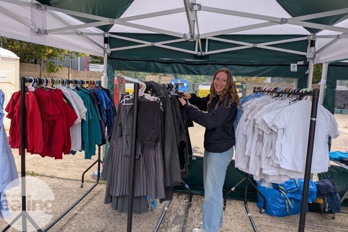 Woman stood between railings with assorted school uniform items