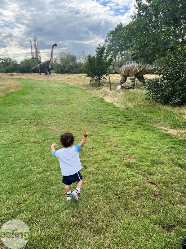 child running in park with dinosaur sculptures