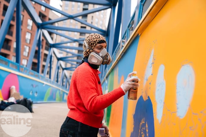 Person wearing a face mask spray painting a bridge